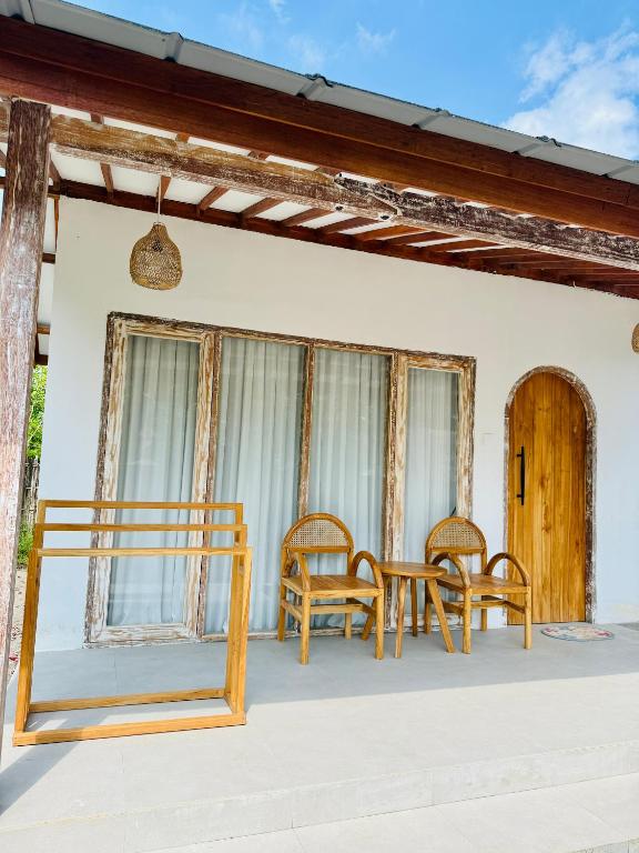 a table and chairs on the front porch of a house at ADIBA village in Gili Meno