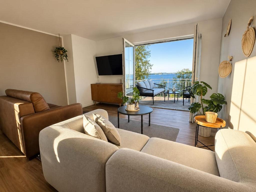 a living room with a couch and a large window at Bei Plön mit Seeblick und großem Balkon in Dersau