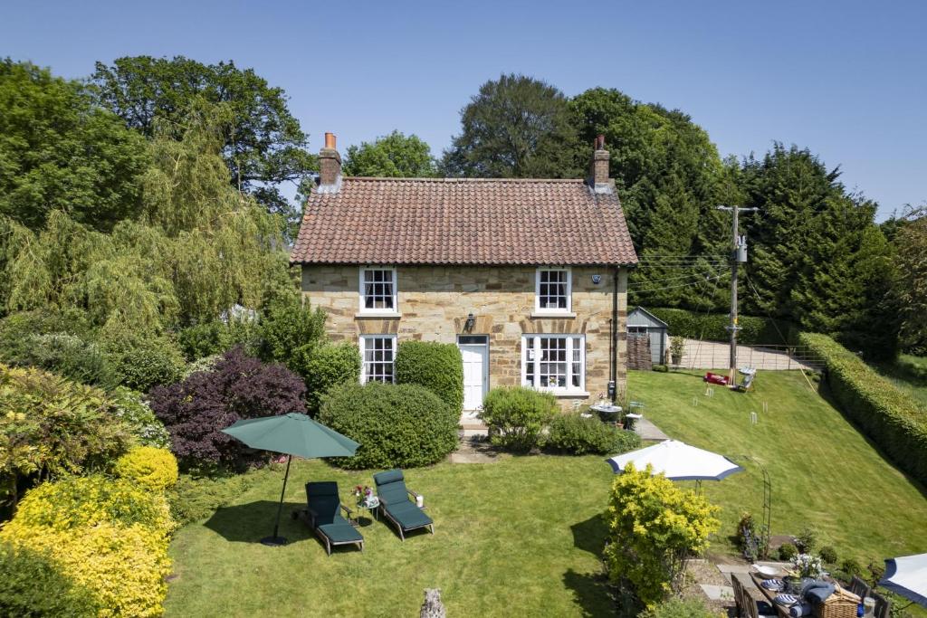 an old stone house with chairs and an umbrella at Virginia Cottage in York