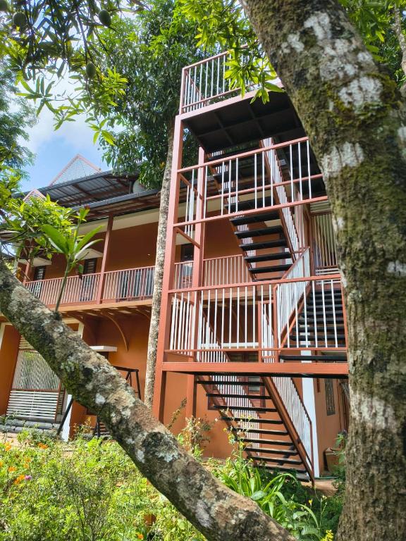 an orange building with stairs in front of it at VARIYATH HOMESTAY THIRUNELLi in Thirunelli