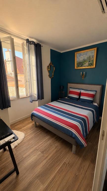 a bedroom with a bed with blue walls at La Garçonnière appartement climatisé in Charolles
