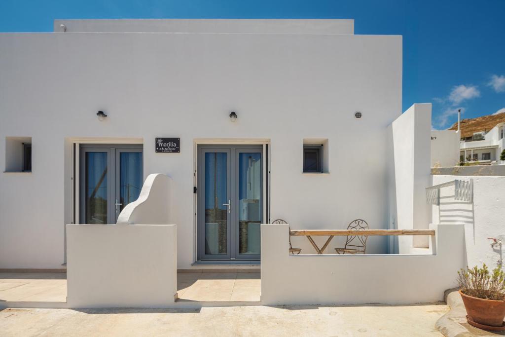 a white house with blue doors and a bench at Marilia Studios in Livadakia
