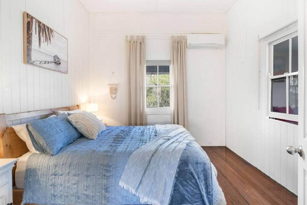 a bedroom with a bed with a blue comforter and a window at 30A Urangan Beach Cottage (Front Property) in Urangan