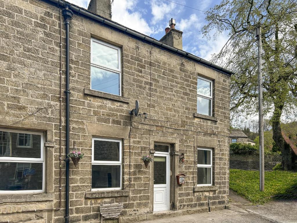 a brick house with a white door and windows at Wolf Bear Tor in Bamford