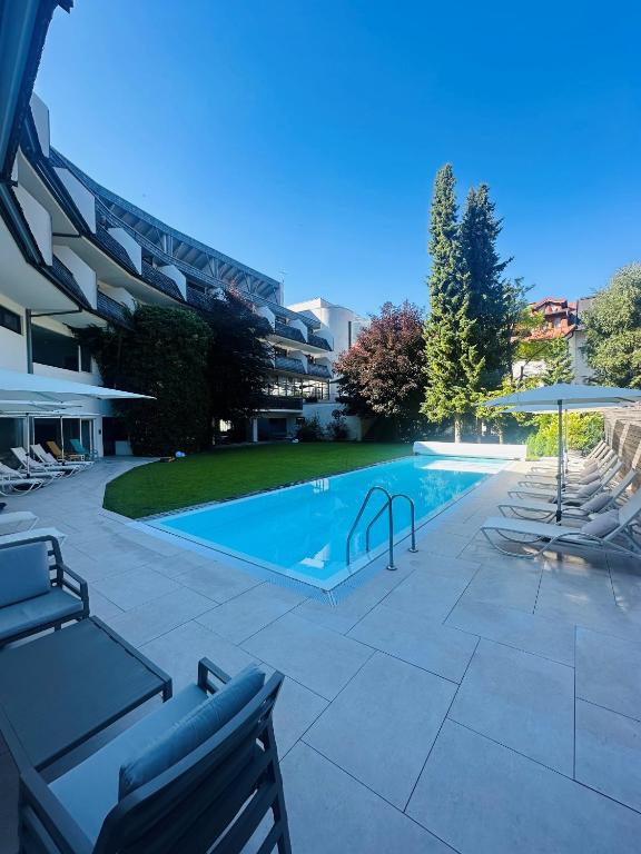 a swimming pool with lounge chairs next to a building at Hotel Rauter in Matrei in Osttirol