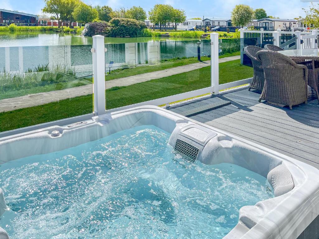a jacuzzi tub on a deck next to the water at Serenity At Lakeside - Uk51947 in Patrington