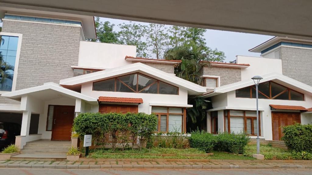 a large white house with windows and bushes at Oasis County Villas in Bangalore