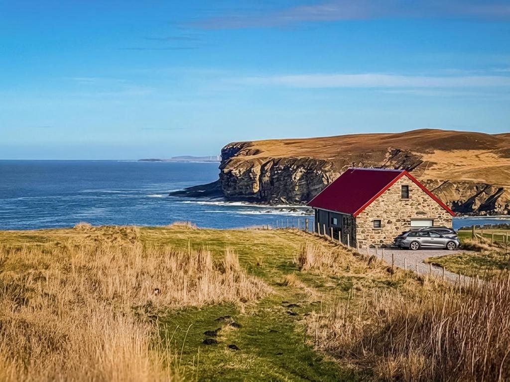 a barn with a car parked next to the ocean at Croft 105 in Melvich