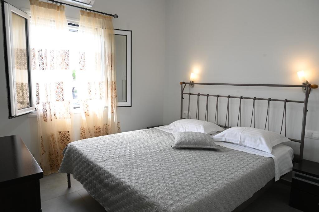 a bedroom with a bed with white sheets and a window at Avra Port House in Porto Heli