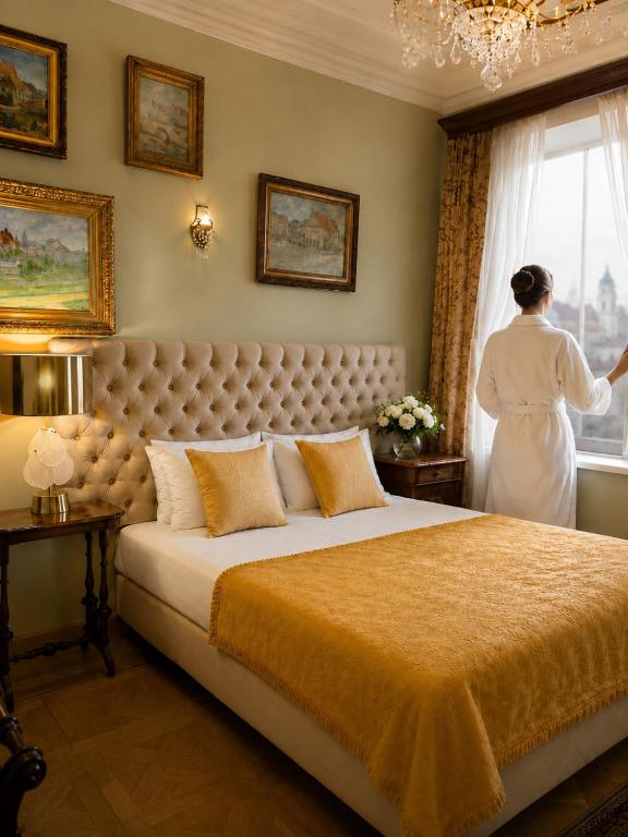 a woman standing in a bedroom looking out the window at Apartamenty Kamienica Muzyków Old Town Lublin in Lublin