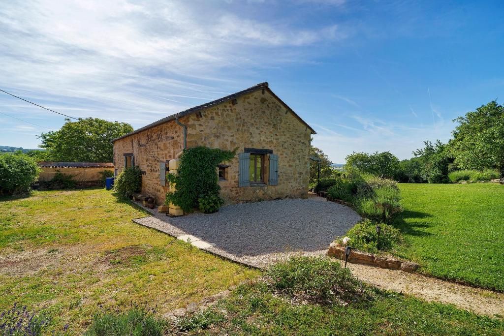 a stone house in a field with a yard at Gite Le Mas in Corgnac-sur-lʼIsle