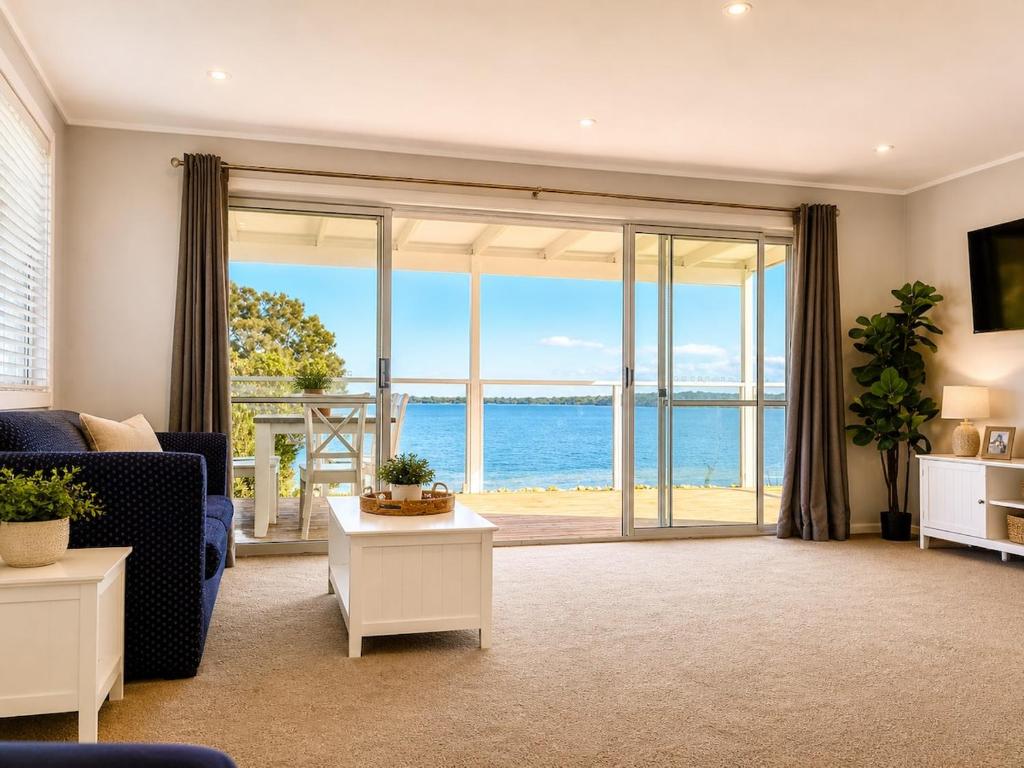 a living room with a view of the ocean at Anita Cottage waterfront in Lake Munmorah