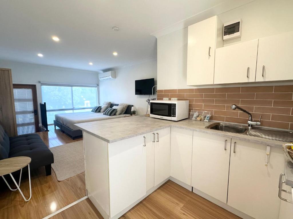 a kitchen with white cabinets and a bed in a room at Studio with private kitchenette and bathroom in Leumeah
