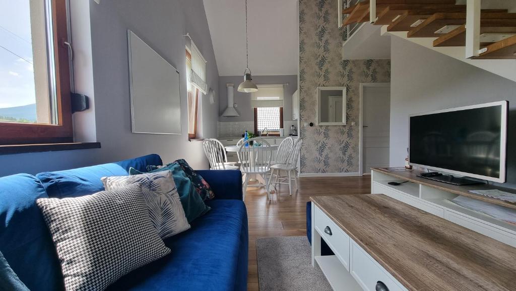 a living room with a blue couch and a tv at domki Stara Morawa in Stronie Śląskie