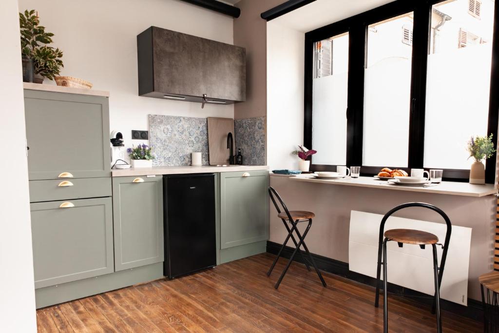 a kitchen with white cabinets and a counter and chairs at Studio Cocoon in Colombey-les-Belles