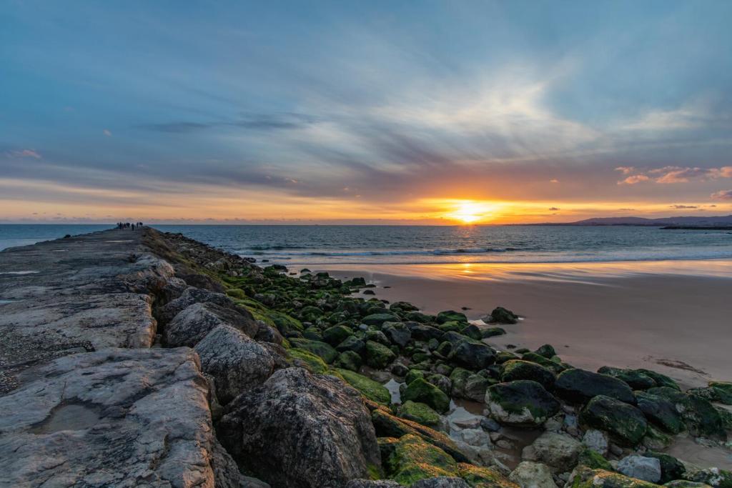 a sunset over the ocean with rocks on the beach at ERRO- Casa Redonda by Villas Aura - Retreat 3 in Aroeira