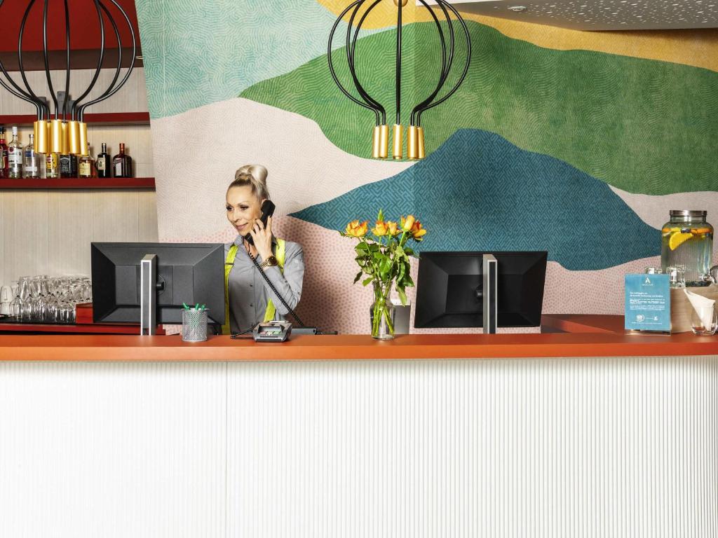 a woman sitting at a counter talking on a phone at ibis Styles St Margrethen Bodensee in Sankt Margrethen