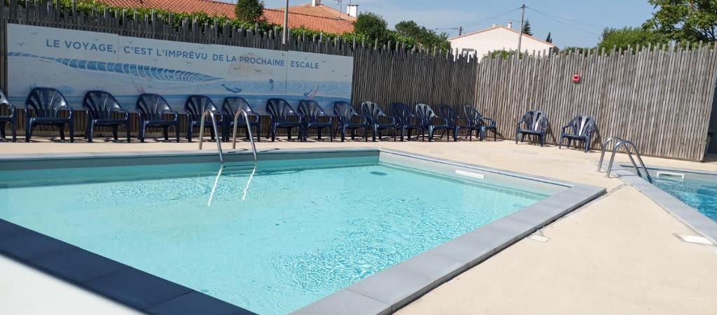 a swimming pool with chairs in front of a fence at le 130 mobile home à Meschers sur Gironde au camping L'escale in Meschers-sur-Gironde