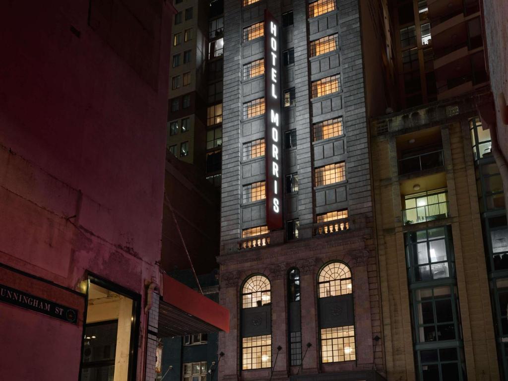 a tall building with a sign on it at night at Hotel Morris Sydney, Handwritten Collection in Sydney