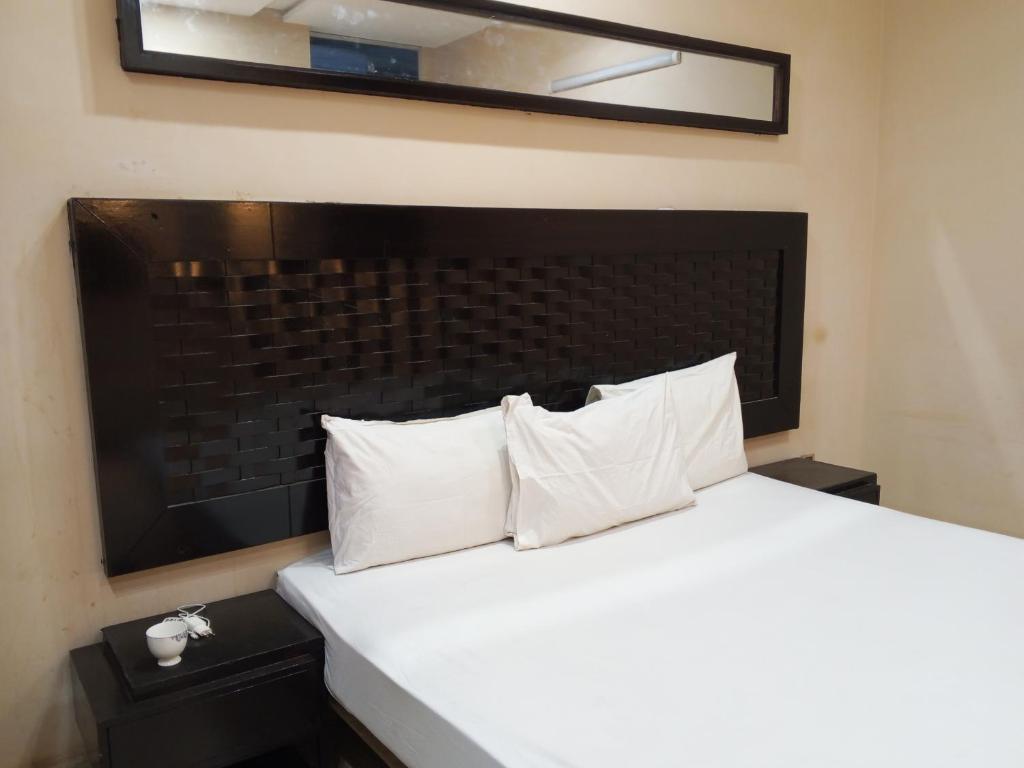 a bedroom with a bed with white pillows and a mirror at Fivee Hotel Model Town Multan in Multan