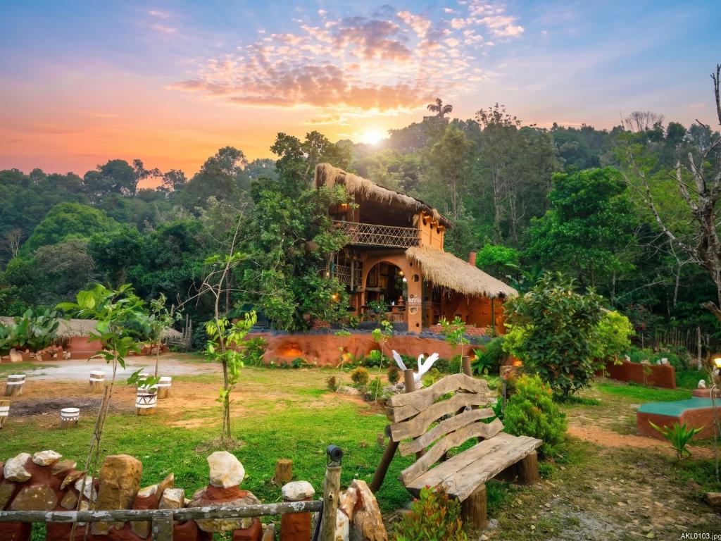 a house in the middle of a field with the sunset at Taiga Forest Mountain Tree house in Wayanad