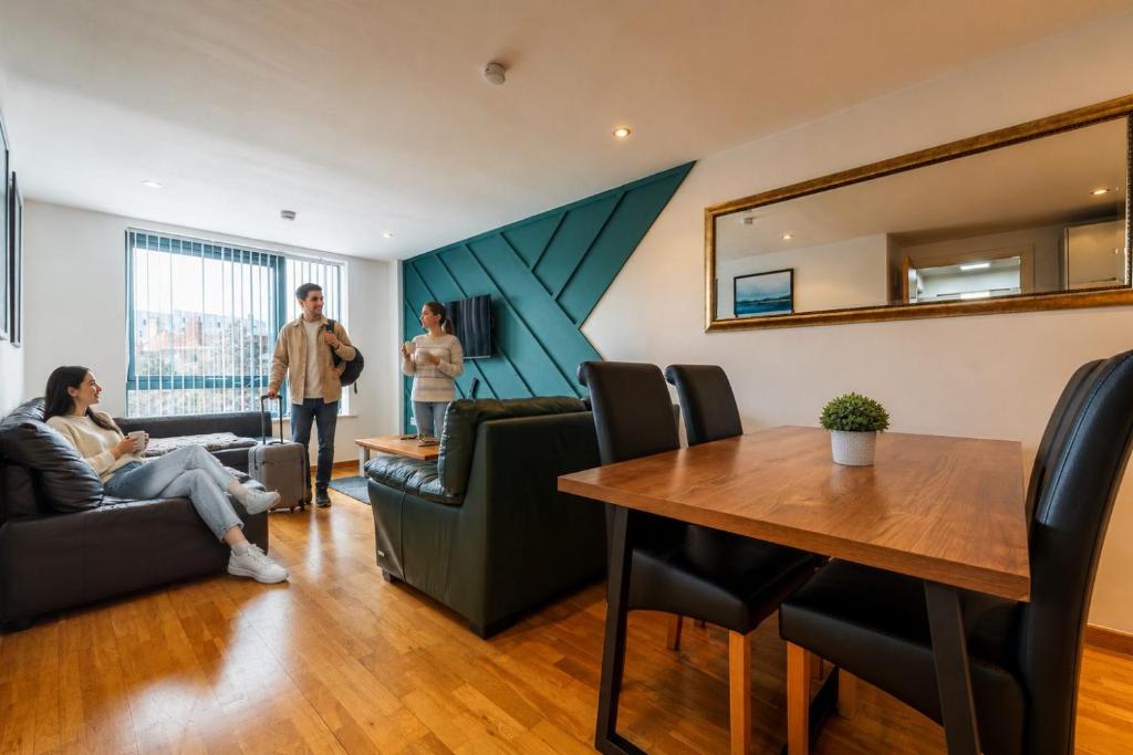 a group of people in a living room with a table at Sidemersey Livings- Rare Accessible 2BR Liverpool City Centre Apartment in Liverpool