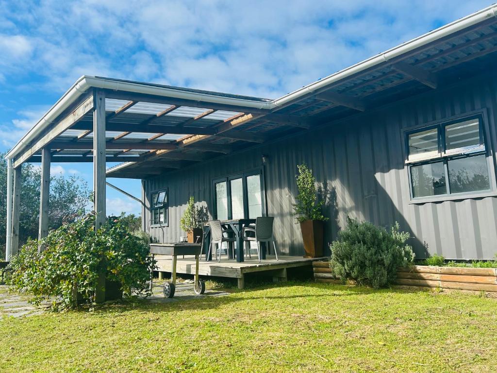 a house with a porch with two chairs and a table at Plett Pods - Casetta del Fuoco - Eco Container Cottage in Plettenberg Bay