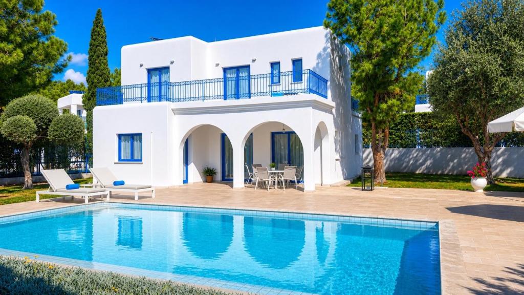 a villa with a swimming pool in front of a house at Azzurro Holiday Villas in Peyia