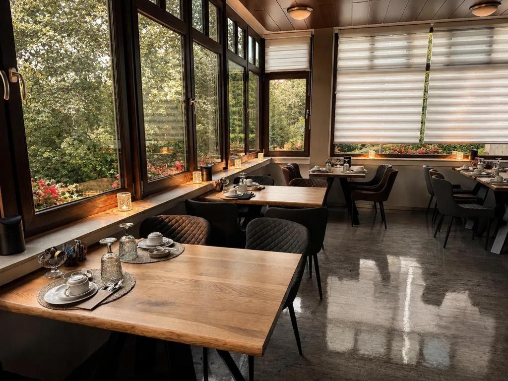 a restaurant with tables and chairs and large windows at Waldhotel Bad Münstereifel in Bad Münstereifel