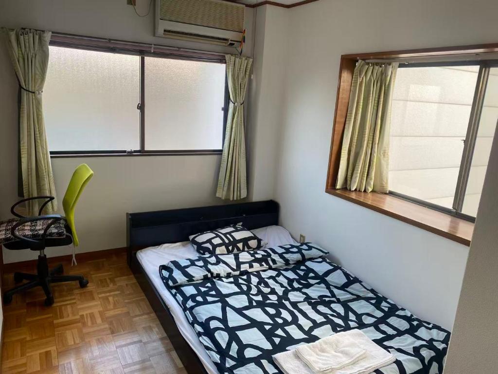 a bedroom with a bed and a chair and two windows at 静佳民宿 in Osaka