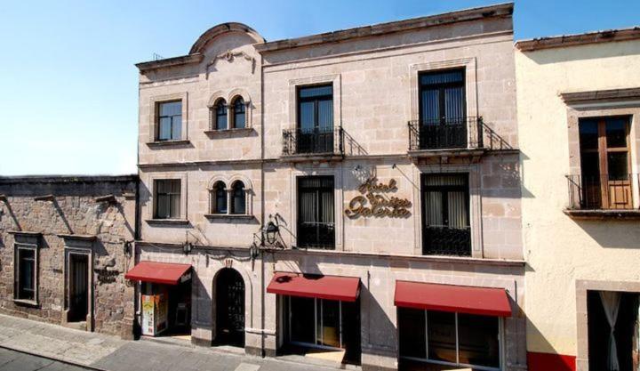a large brick building with red awnings on it at Hotel & Suites Galeria in Morelia