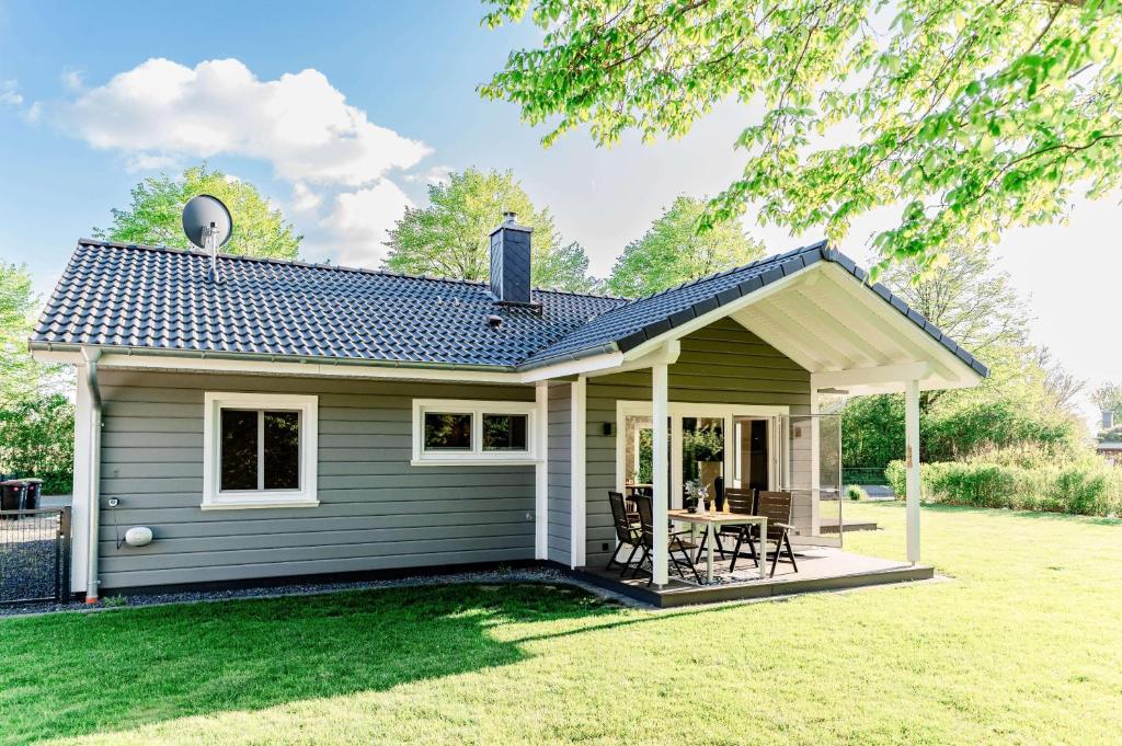 a small green house with a table and chairs at Fördezauber - Ruhiges Ferienhaus mit eingezäuntem Garten und Kamin in Bönstrup