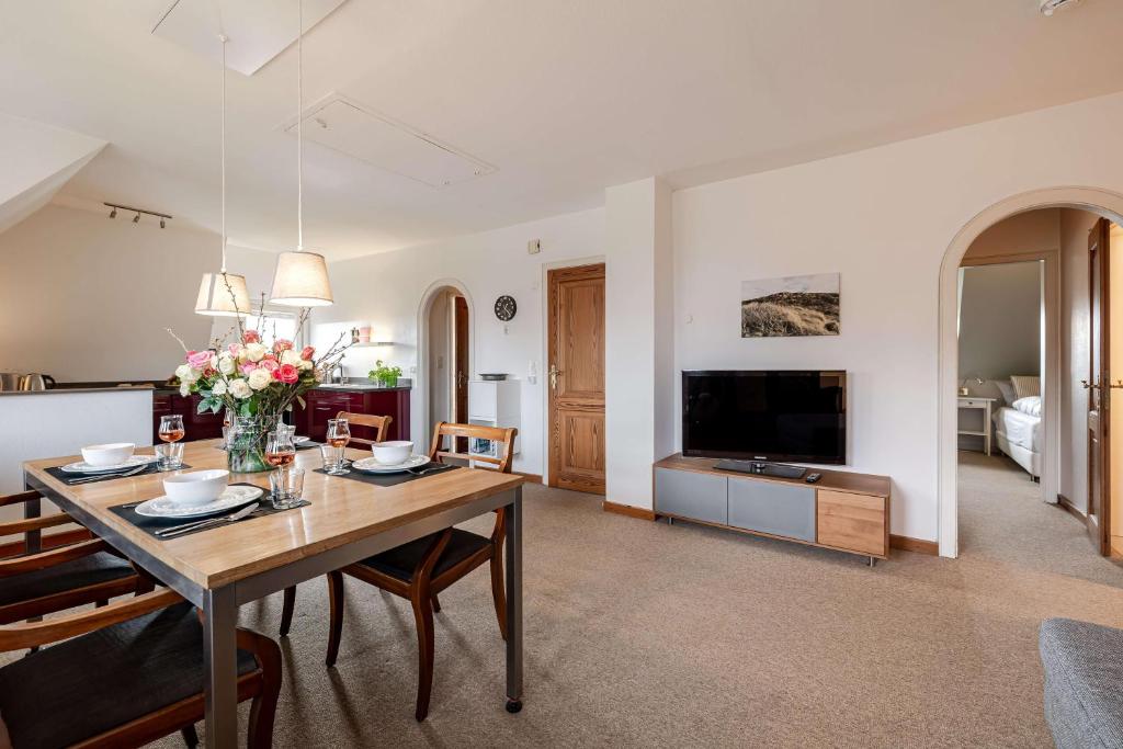 a living room with a dining table and a television at Haus Wattblick OG in Braderup