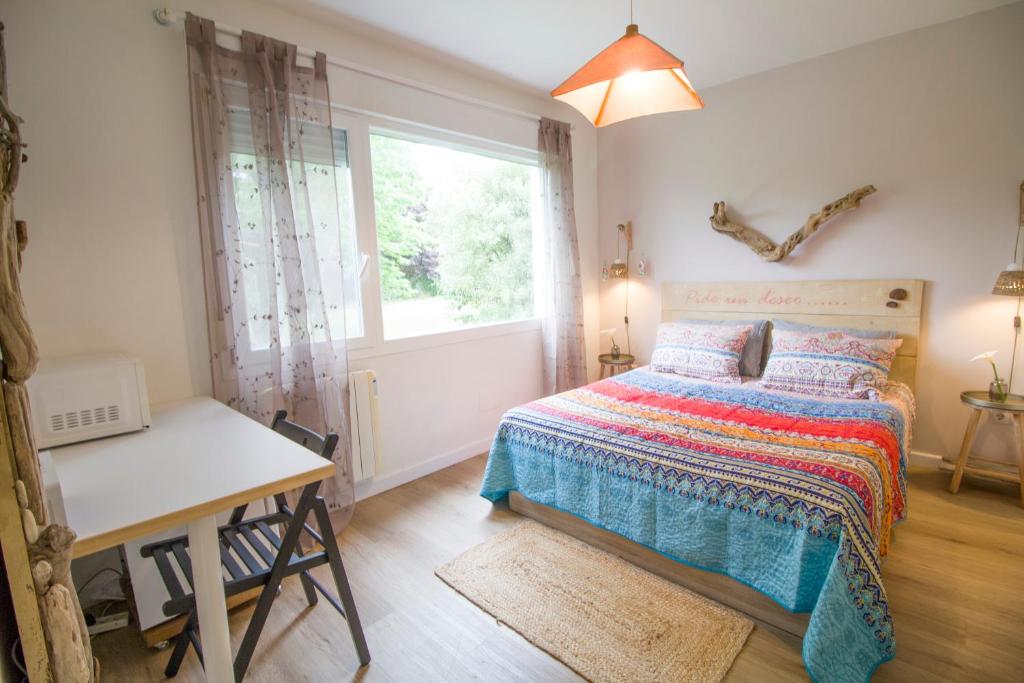 a bedroom with a bed and a desk and a window at La Casa del Petirrojo de Ribamontan al Mar con Surf y Tranquilidad in Castanedo