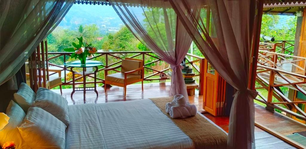 a bedroom with a bed and a balcony with a table at Camelliana Horizon Pongyang - Nature Retreat in Mae Rim