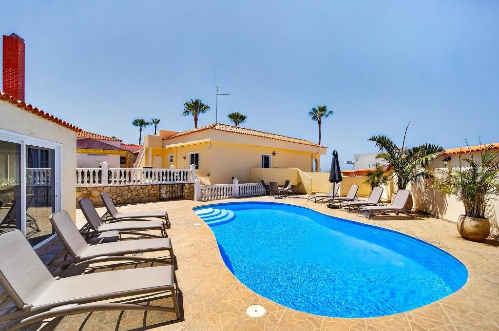 a villa with a swimming pool and lounge chairs at Spacious Villa Victoria Heated Pool in Callao Salvaje