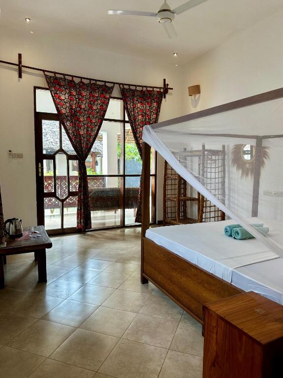 a bedroom with a bed with a canopy and windows at vayana nungwi in Nungwi