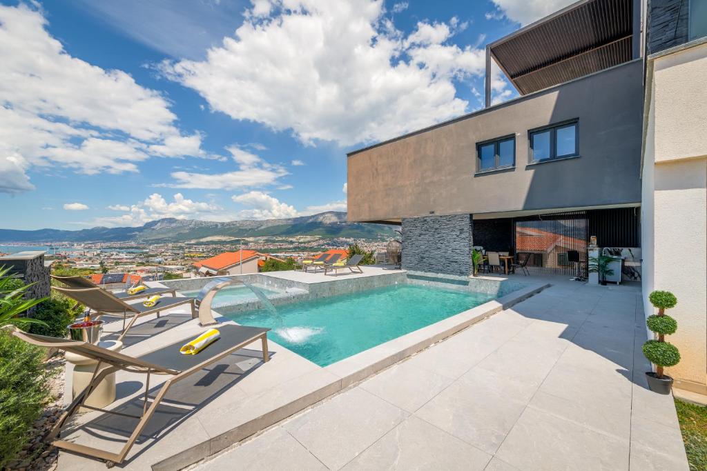 a house with a swimming pool and two chairs at Panorama Coastal Haven in Split