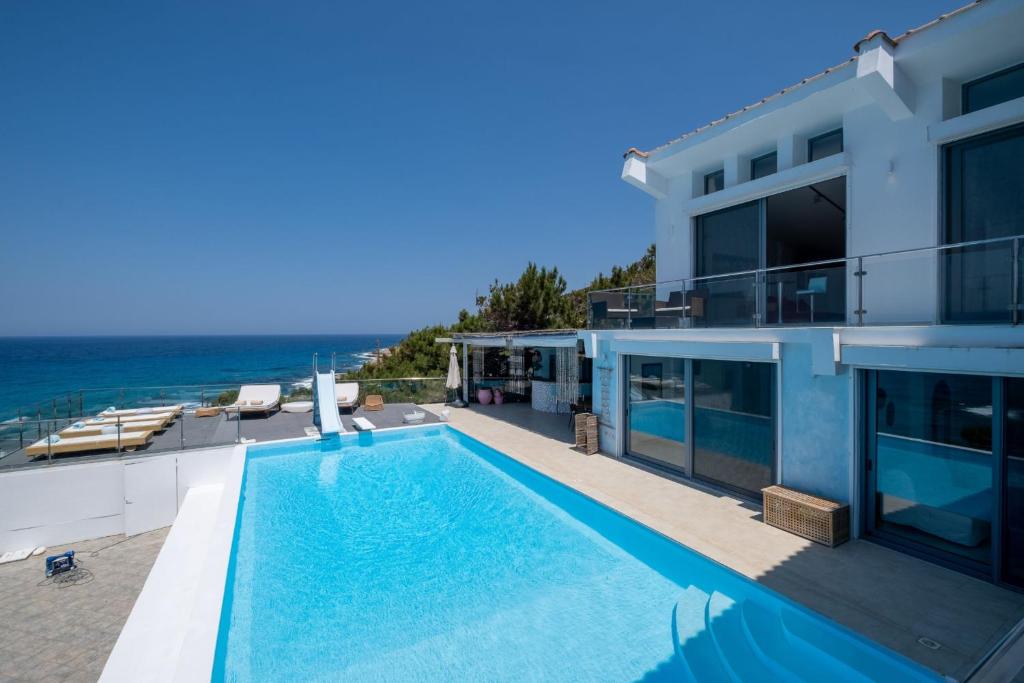 a view of a house with a swimming pool and the ocean at Icarus Luxury Beachfront Villa in Gialiskari