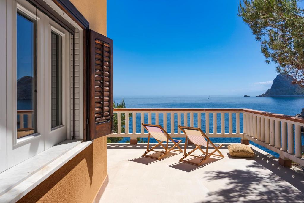 a balcony with two chairs and a view of the ocean at Seafront Collection - Bungalows and Villas in Aspra