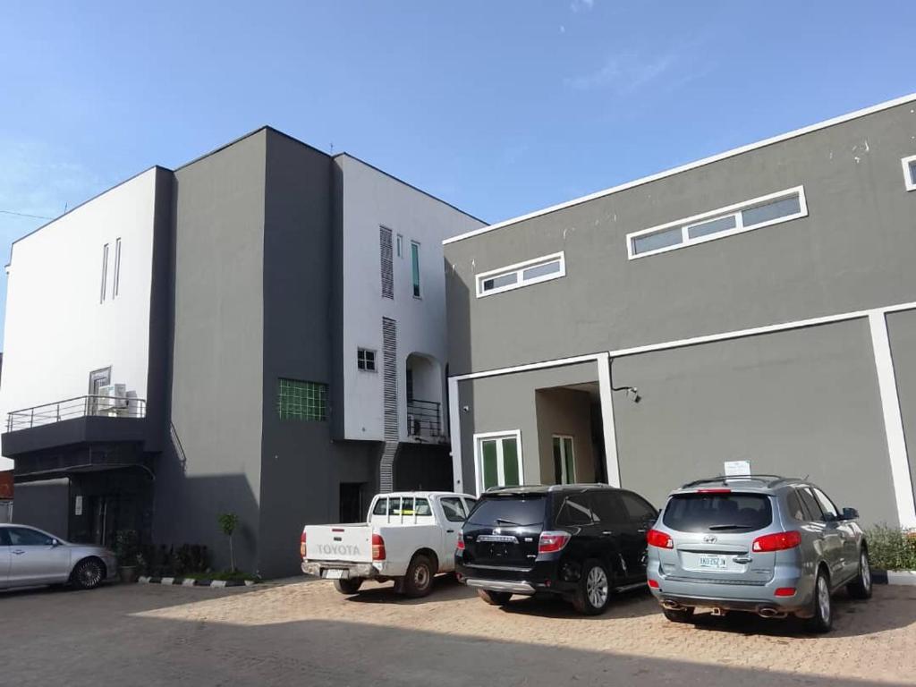 two cars parked in a parking lot in front of a building at Wesley Hotels in Benin City