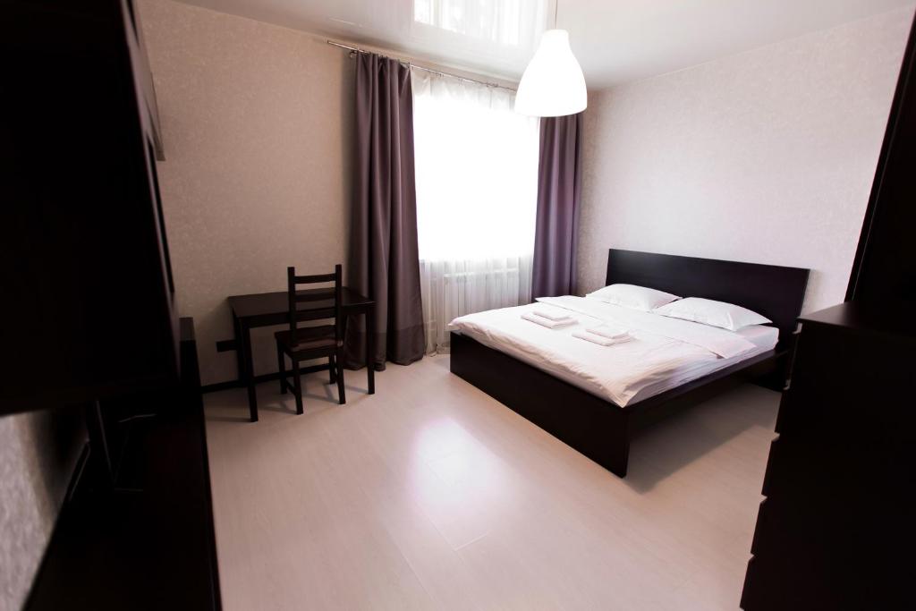 ノヴォシビルスクにあるApartments Domant Romanova 60のベッドルーム1室(ベッド1台、椅子、窓付)