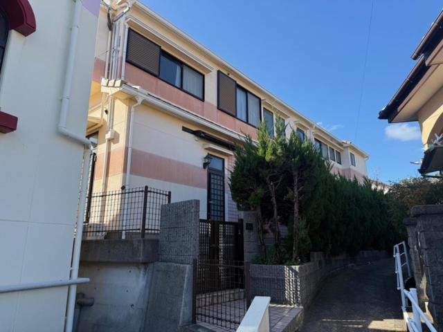 a building with a fence in front of it at GATE80長崎 坂の街長崎 無人宿 完全セルフ 予約メッセージ欄確認要す スマートロック 暗証番号チェックイン 素泊まり専門 アメニティ持参で格安滞在 セコム24h監視 駐車場4台 in Nagasaki