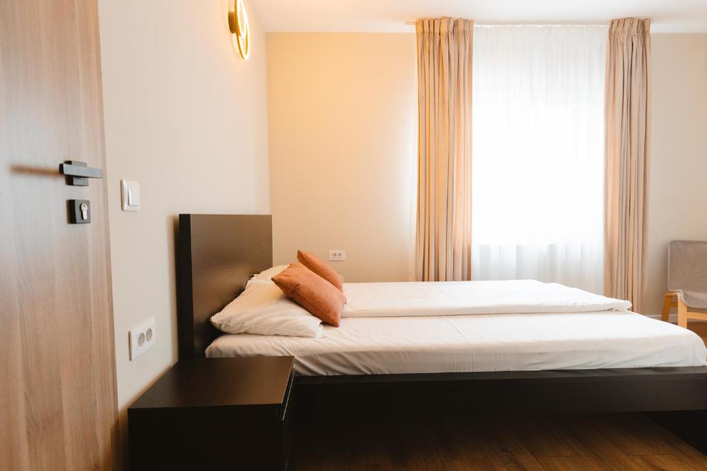 a bedroom with a bed with white sheets and a window at Pensiunea Mario in Beiuş