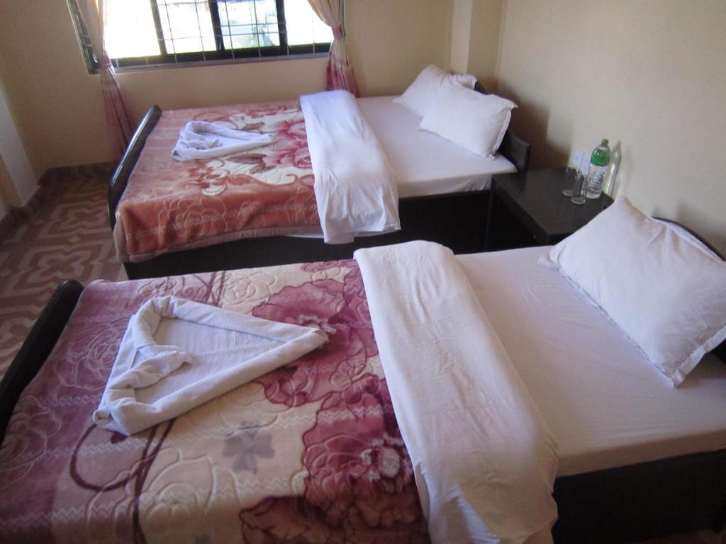 two beds in a hotel room with towels on them at Hotel Sunflower in Pokhara