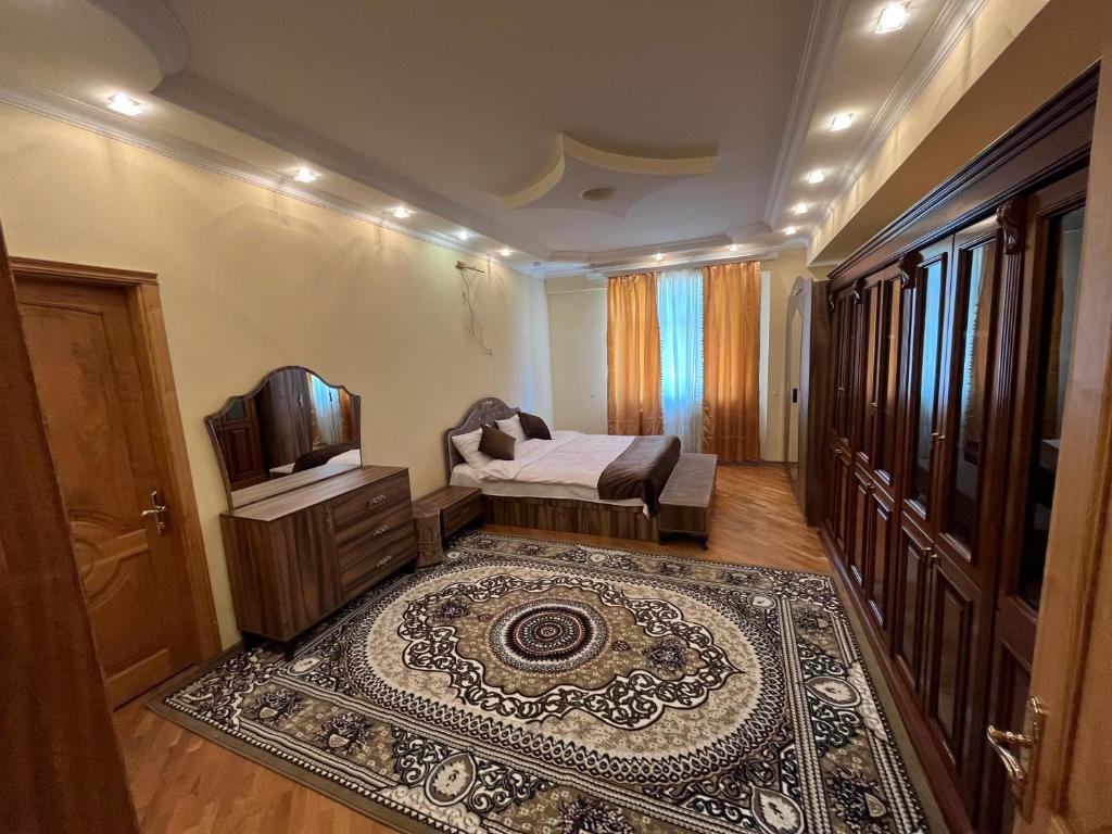 a room with a bed and a tv and a rug at Rahat Ev in Ganja