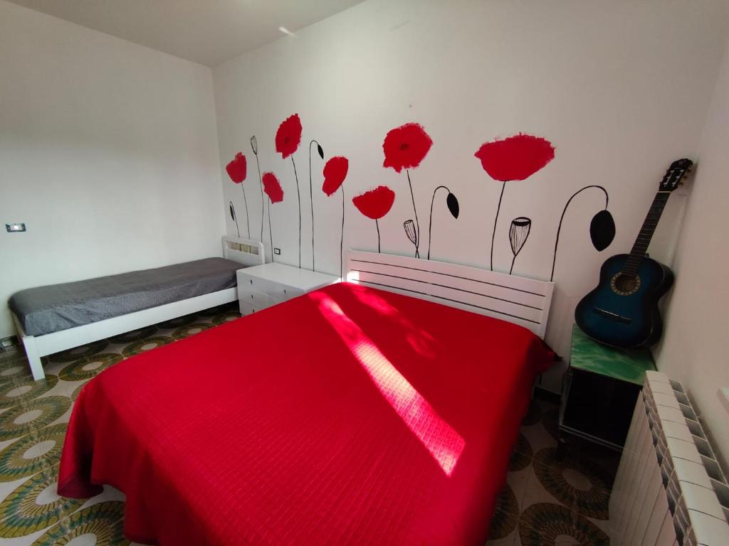 a bedroom with a bed with a red blanket and a guitar at Country House Atessa in Atessa