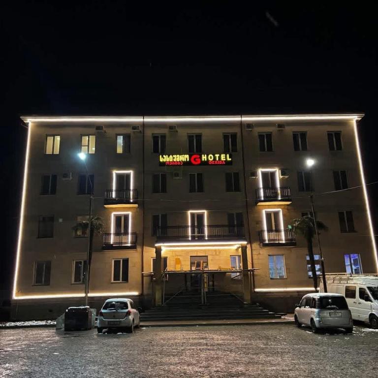 a large building with cars parked in a parking lot at Hotel okriba in Tqibuli