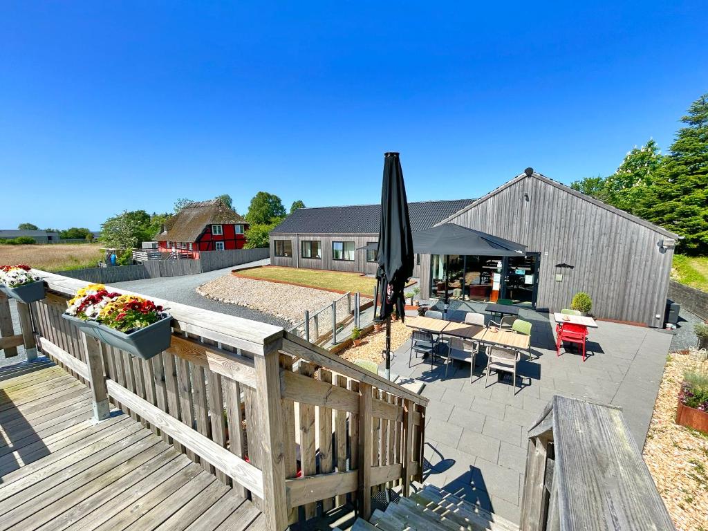 a wooden deck with an umbrella and a patio at Denmark Outdoor Lodge in Ebberup