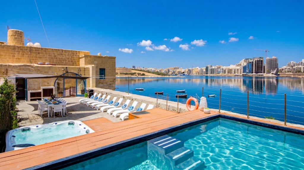 a swimming pool on a deck with a view of the water at Valletta Waterfront Villa with Pool and Jacuzzi in Valletta